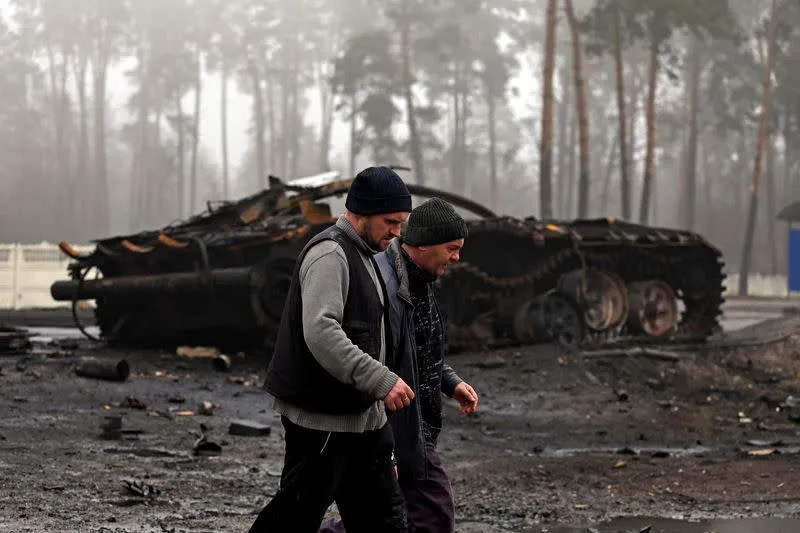 FILE PHOTO: Residents walk past a destroyed Russian tank, in Dmytrivka village