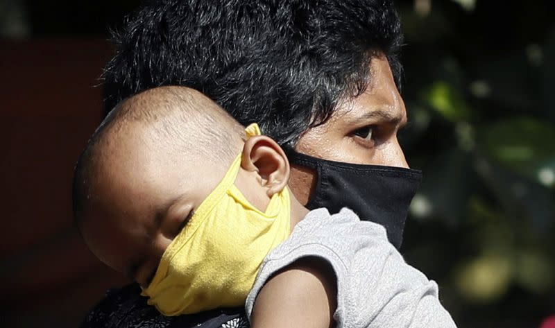 A person wearing a protective mask carries a child inside the premises of a hospital, where a special ward has been set up for treating the coronavirus disease, in Mumbai