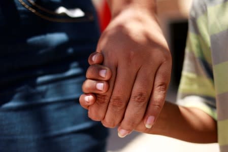 Honduran migrant Denia Carranza, 24, and her son Robert, 7, who have given up their U.S. asylum claim under the Migrant Protection Protocol (MPP), hold hands at Casa del Migrante migrant shelter, in Ciudad Juarez