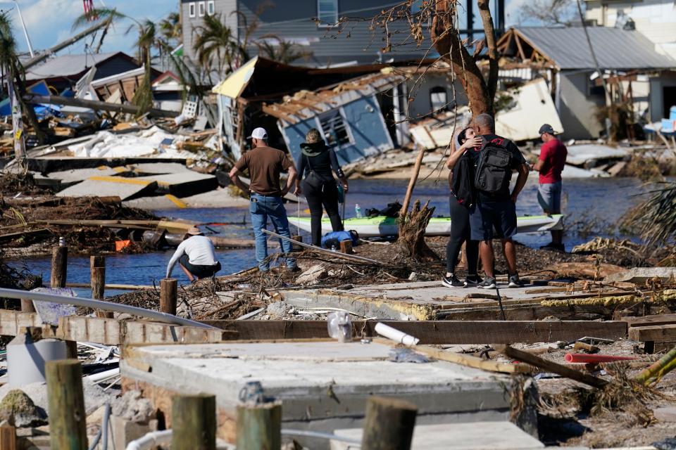 FILE - People stand on the destroyed bridge to Pine Island as they view the damage in the aftermath of Hurricane Ian in Matlacha, Fla., Sunday, Oct. 2, 2022. The only bridge to the island is heavily damaged so it can only be reached by boat or air. Hurricane Ian has resulted in at least 79 people confirmed dead, including 71 in Florida, as hundreds of thousands of people wait for power to be restored. (AP Photo/Gerald Herbert, File)