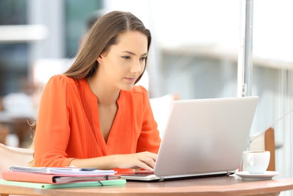 Female student with orange shirt working on a notebook computer