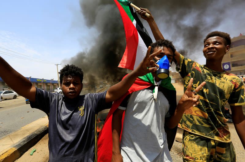 Civilians with the national flags gestures at a barricade as members of Sudanese pro-democracy group demonstrate on the anniversary of a major anti-military protest, as groups loyal to toppled leader Omar al-Bashir plan rival demonstrations in Khartoum