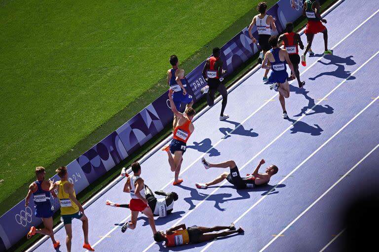 El español Thierry Ndikumwenayo, Dominic Lokinyomo Lobalu del equipo de refugiados, el británico George Mills y el holandés Mike Foppen caen mientras compiten en la serie masculina de 5.000 metros de la prueba de atletismo de los Juegos Olímpicos de París 2024 en el Stade de France en Saint-Denis