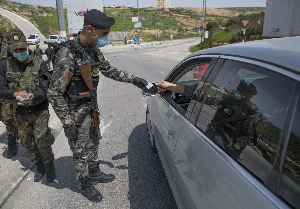 Palestinian security forces are deployed to enforce new government measures against the coronavirus, in the West Bank city of Ramallah, Monday, March 23, 2020. On Sunday, Palestinian Prime Minister Mohammad Shtayyeh declared a two week set of strict precautionary measures that include confining residents to their homes, restricting movement between cities and deploying security forces, along with other measures to contain the COVID-19 outbreak. (AP Photo/Nasser Nasser)