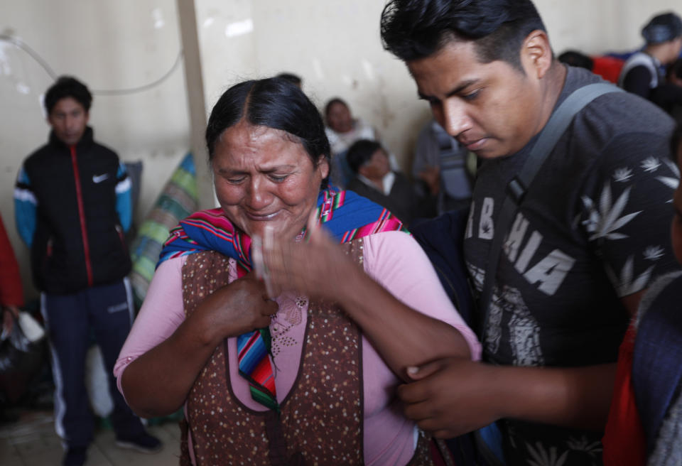 A woman cries where bus crash victims lie on the ground at the coca leaf market where the late farmers used to bring their coca harvest to sell, as a wake is held in La Paz, Bolivia, Friday, Jan. 31, 2020. A bus missed a curve on a road near Bolivia’s capital on Friday and plunged down a ravine, killing at least 14 people and injuring 19 more, officials said. (AP Photo/Juan Karita)