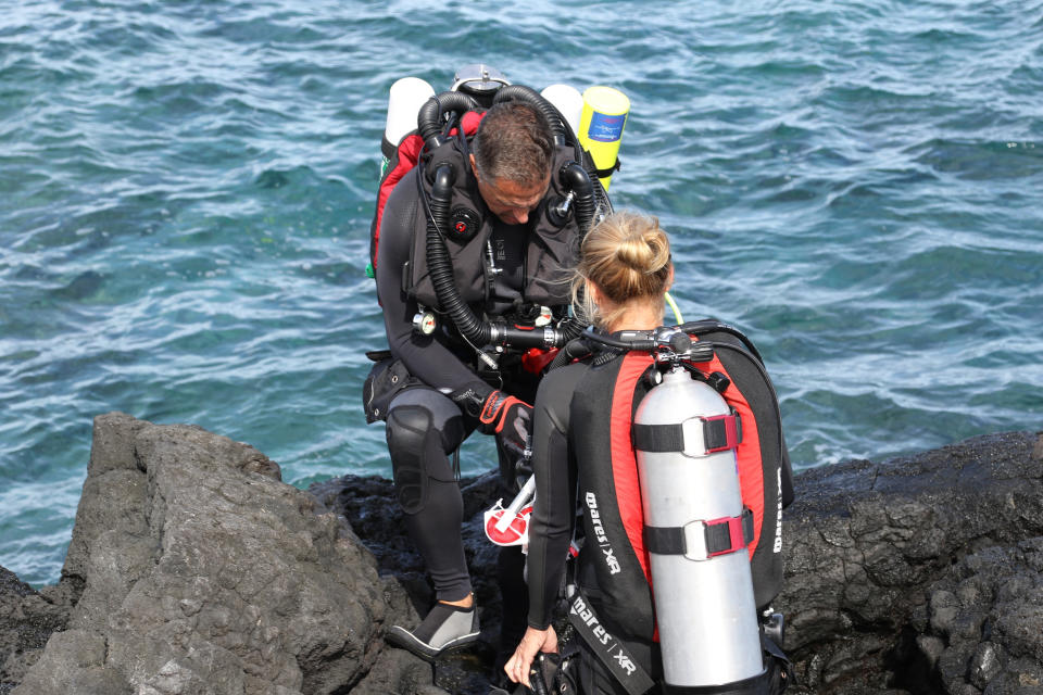 FILE - In this Sept. 13, 2019, file photo, Greg Asner, left, director of the Center for Global Discovery and Conservation Science at Arizona State University, prepares to dive on a coral reef off the Big Island near Captain Cook, Hawaii. Flooding in March 2021 in Hawaii caused widespread and obvious damage, and the runoff from these increasingly severe storms is also threatening Hawaii's coral reefs. Although coral reefs worldwide face threats from global warming, including marine heatwaves that bleach and kill coral, storm runoff could prove a more serious and immediate threat to reefs in the state. "In Hawaii, I would rate runoff much higher than marine heatwaves in driving coral decline," said Asner. (AP Photo/Caleb Jones, File)