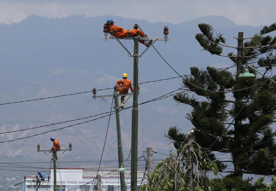 In this Saturday, Oct. 6, file photo, a worker rests on top of a pole as they restore electricity at the earthquake-hit Balaroa neighborhood in Palu, Central Sulawesi, Indonesia. (AP Photo/Aaron Favila, File)