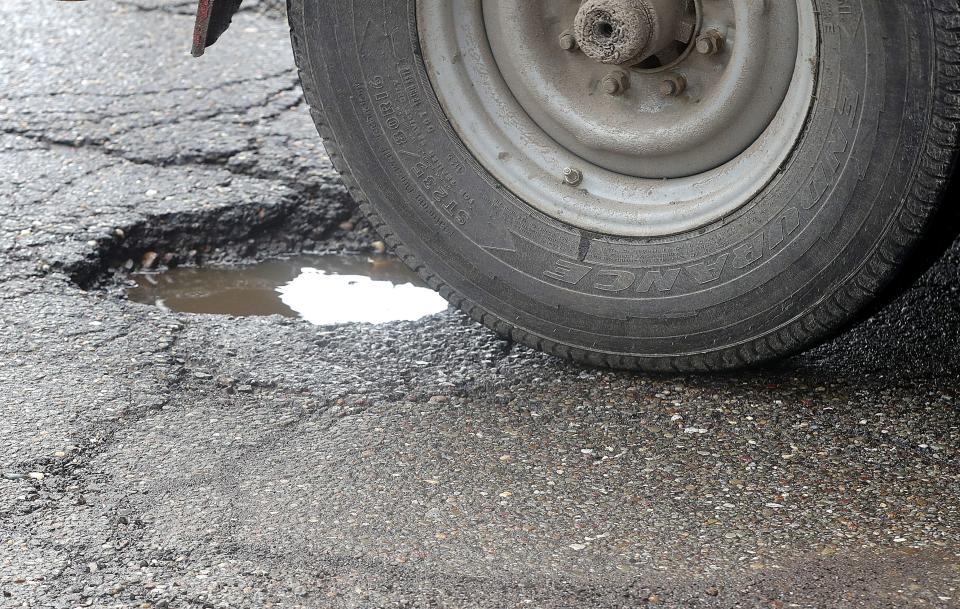 A vehicle travels across a pothole on East Exchange Street in Akron.