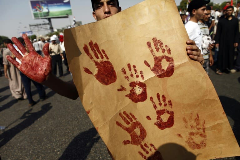 A supporter of the Muslim Brotherhood and ousted Egyptian president Mohamed Morsi shows his blood-stained hand while holding a placard bearing handprints made with the blood of victims who were shot during a gun battle