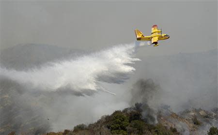 A "super scooper" air tanker makes waters drops as firefighters battle a fast-moving California wildfire, so-called the "Colby Fire", in the hills of Glendora January 16, 2014. REUTERS/Gene Blevins