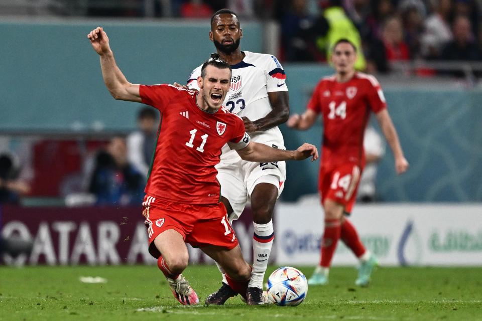 USA's midfielder #23 Kellyn Acosta fouls Wales' forward #11 Gareth Bale to receive a yellow card during the Qatar 2022 World Cup Group B football match between USA and Wales at the Ahmad Bin Ali Stadium in Al-Rayyan, west of Doha on November 21, 2022. (Photo by Jewel SAMAD / AFP) (Photo by JEWEL SAMAD/AFP via Getty Images)