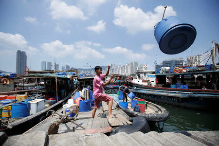 A fisherman works on an anchored boat at a fishing harbour as Typhoon Mangkhut approaches, in Shenzhen, China September 15, 2018. REUTERS/Jason Lee