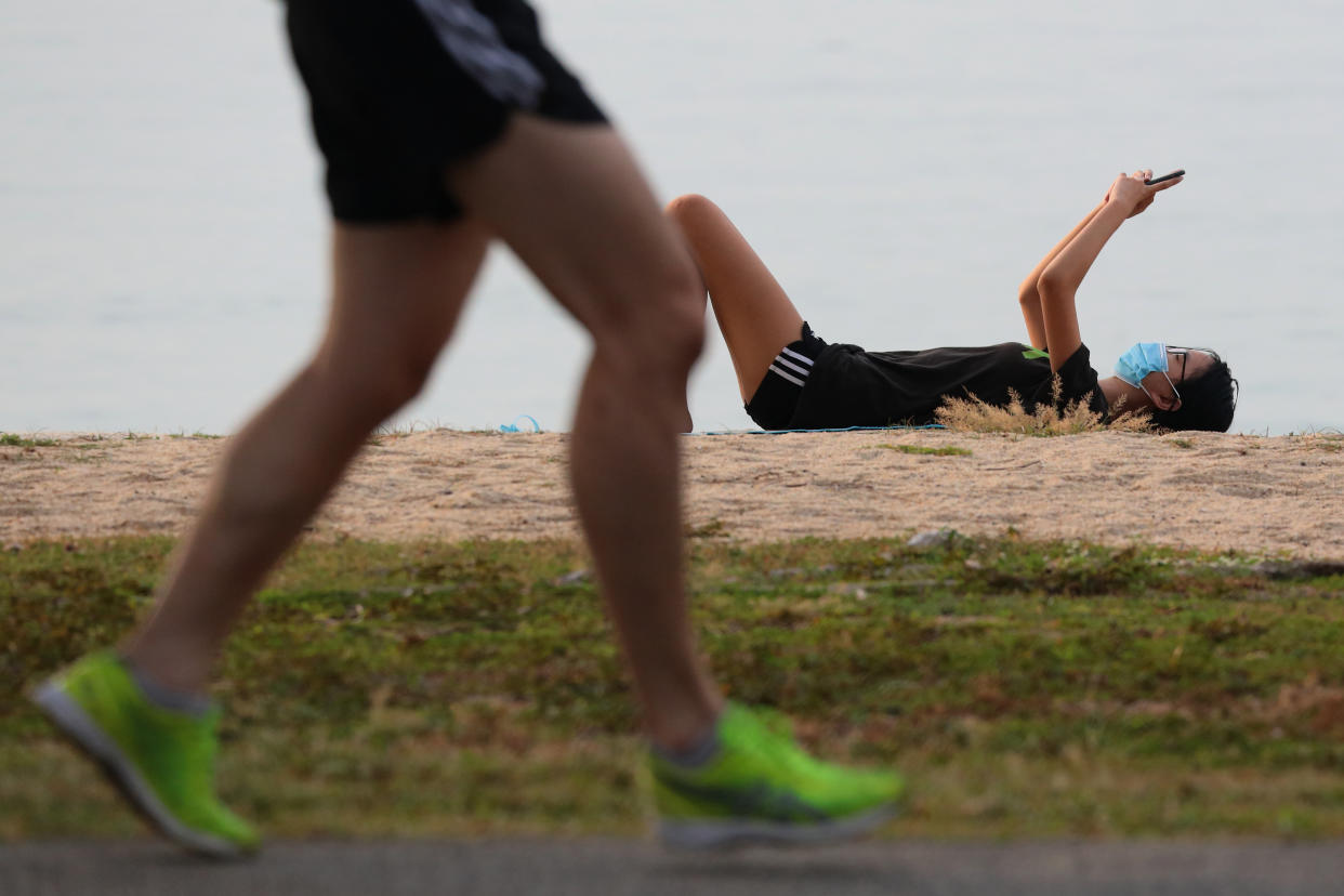 A man wearing protective mask uses his phone at a park on October 17, 2021 in Singapore. (Photo by Suhaimi Abdullah/NurPhoto via Getty Images)