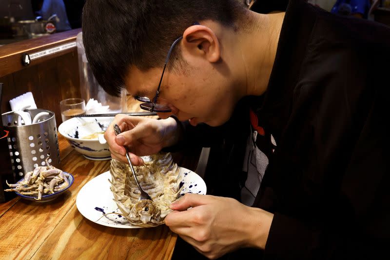 General Kiang, 28, one of the two reserved customers eats the giant isopod in Taipei