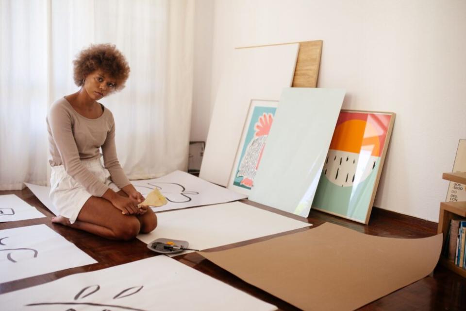 Black woman sitting on the floor surrounded by art