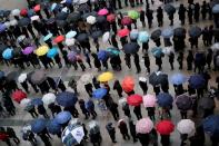 People wearing masks after the coronavirus outbreak wait in a line to buy masks as it rains in front of a department store in Seoul