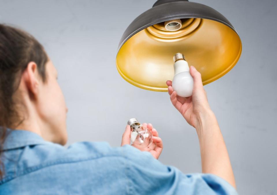 Woman changing the light bulb in a ceiling light fixture.