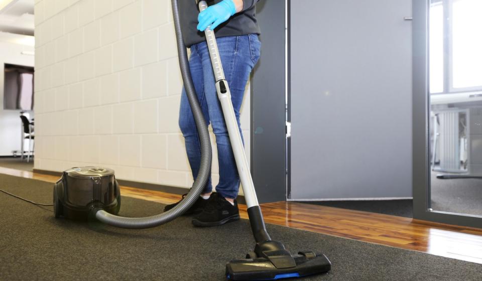 A woman cleaning her carpet with vacuum