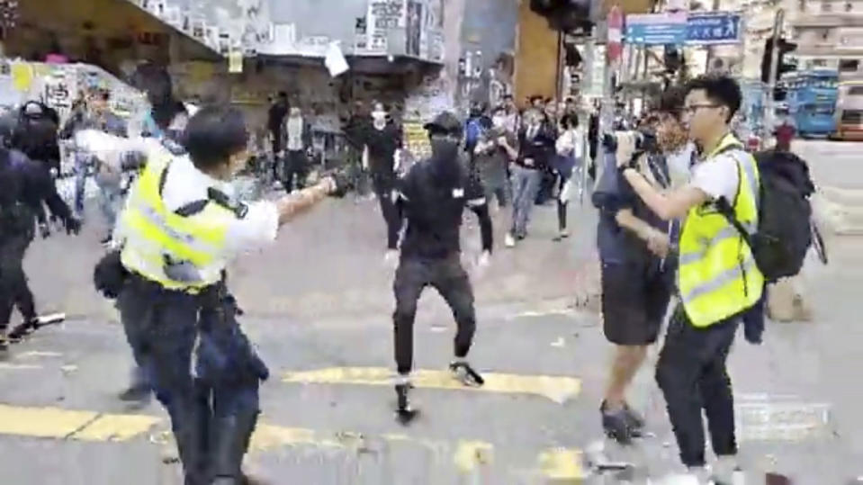 In this image made from video, a police officer, left, prepares to shoot a protester, center, in Hong Kong Monday, Nov. 11, 2019. The police shot the protester as demonstrators blocked subway lines and roads during the Monday morning commute. (Cupid Producer via AP)