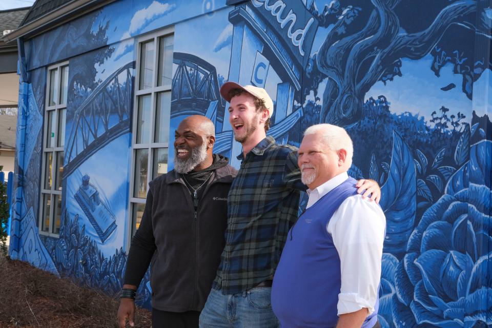 Feb 14, 2023; Tuscaloosa, AL, USA; A new mural on the wall of Alabama One credit union in Alberta is designed with the rebirth of Alberta in mind. Artist Banks Compton, center, poses for a photo with Alabama One Chief Growth Officer Martin Houston, left, and CEO Bill Wells, right.