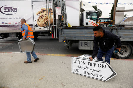 A worker holds a road sign directing to the U.S. embassy, in the area of the U.S. consulate in Jerusalem, May 7, 2018. REUTERS/Ronen Zvulun