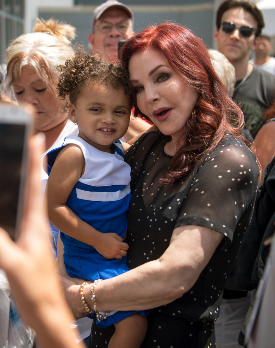 Priscilla Presley holds a child while greeting fans at Graceland