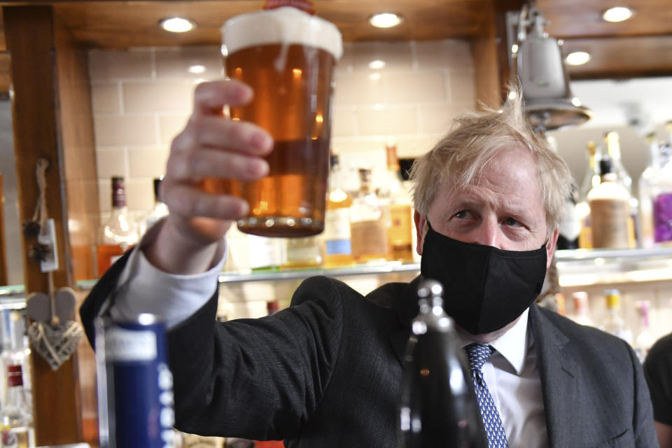 Britain's Prime Minister Boris Johnson holds up a pint during a visit to The Mount pub and restaurant in Wolverhampton, central England, Monday April 19, 2021, during the Conservative party election campaign. (Jacob King/Pool via AP)