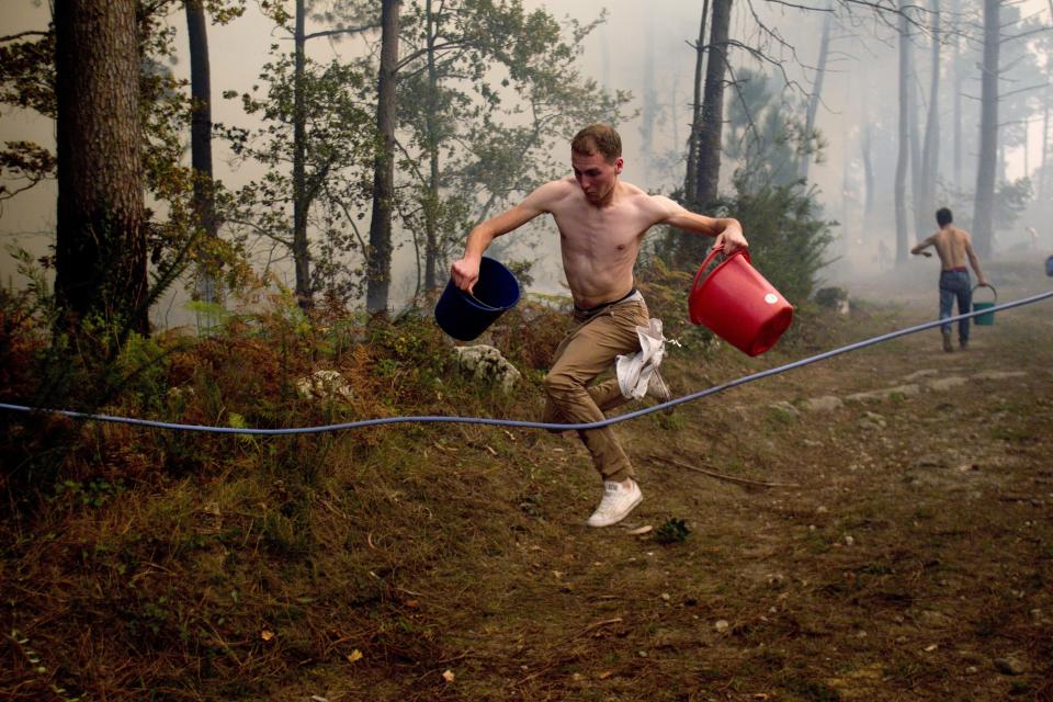 <span class><span class>Un residente se dispone a llenar cubos de agua mientras colabora en la extinción de un incendio forestal en la zona de Zamanes, en Vigo, Galicia, noroeste de España, el 15 de octubre de 2017. (Foto: Salvador Sas / EPA-EFE / REX / Shutterstock)</span></span>