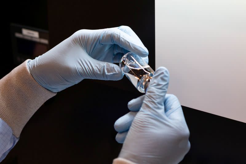 A lab technician visually inspects a filled vial of investigational remdesivir at a Gilead Sciences facility in La Verne