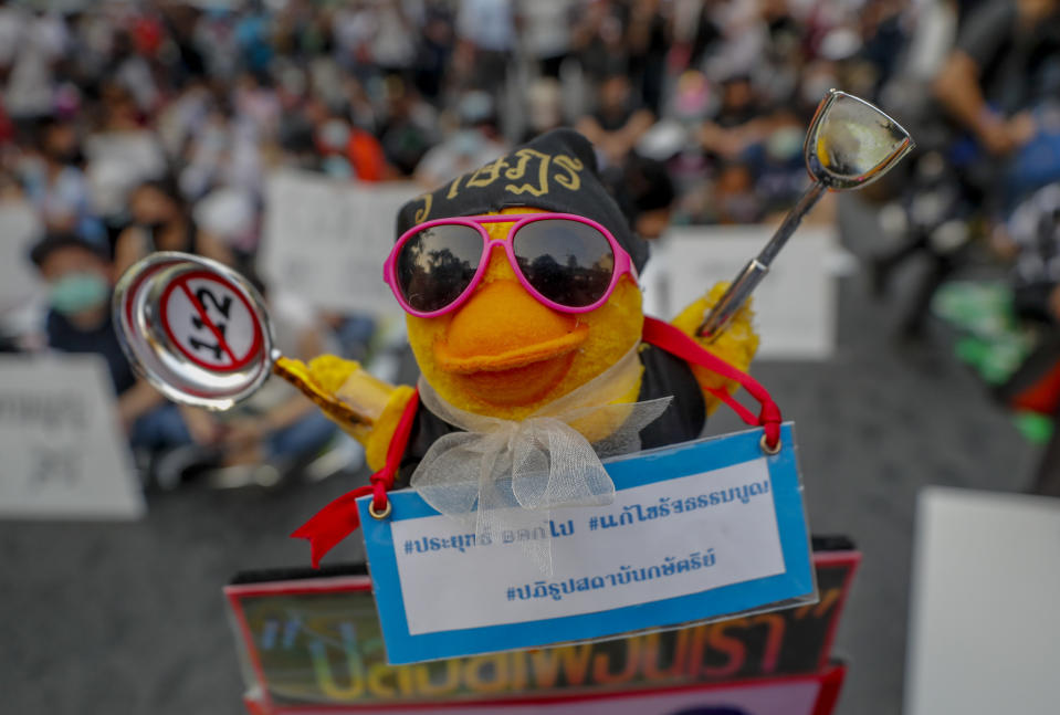 A yellow toy duck, a recent symbol of pro-democracy protesters, has a scarf with a message attached during a rally in Bangkok, Thailand, Wednesday, March 24, 2021, ahead of an indictment against 13 protest leaders on Thursday for allegations of sedition and defaming the monarchy. Message translates as "Prayuth get out, the constitution to be amended, the monarchy's reform." (AP Photo/Sakchai Lalit)