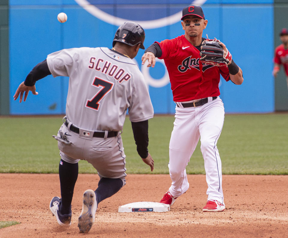 Cleveland Indians' Andres Gimenez forces Detroit Tigers' Jonathan Schoop at second base and throws to first to complete a double play during the fourth inning of a baseball game in Cleveland, Sunday, April 11, 2021. (AP Photo/Phil Long)