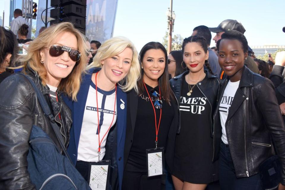 felicity huffman, elizabeth banks, eva longoria, olivia munn, and lupita nyong'o pose for a photo with a crowd of people behind them as they stand outside