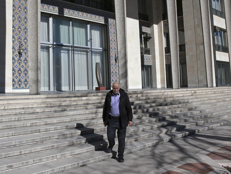 In this Tuesday, Jan. 15, 2019 photo, Jamal Shahosseini, 63, who as a young revolutionary raided the Niavaran Palace with other demonstrators and presently works security at the palace, walks down the the steps of the palace that was the primary and last residence of late Shah Mohammad Reza Pahlavi and his family prior to leaving Iran for exile during the 1979 Islamic Revolution, in northern Tehran, Iran. The palace complex of mansions on a 27-acre plot, now a museum, nestled against the Alborz Mountains, welcomes the public to marvel at the luxuries the shah enjoyed as Iran's monarch for nearly four decades. (AP Photo/Vahid Salemi)