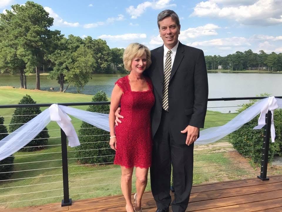Kate Connors wearing a red dress standing with her late husband, Don outside by a lake