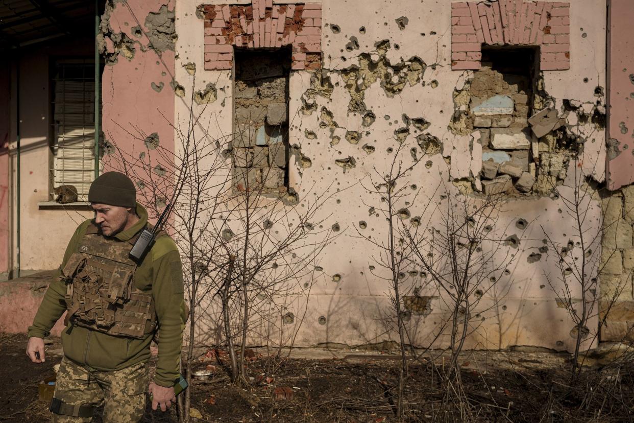 A Ukrainian serviceman walks by a bullet-riddled wall of a house near the frontline village of Krymske, Luhansk region, in eastern Ukraine, Saturday, Feb. 19, 2022. Ukrainian President Volodymyr Zelenskyy, facing a sharp spike in violence in and around territory held by Russia-backed rebels and increasingly dire warnings that Russia plans to invade, on Saturday called for Russian President Vladimir Putin to meet him and seek resolution to the crisis.