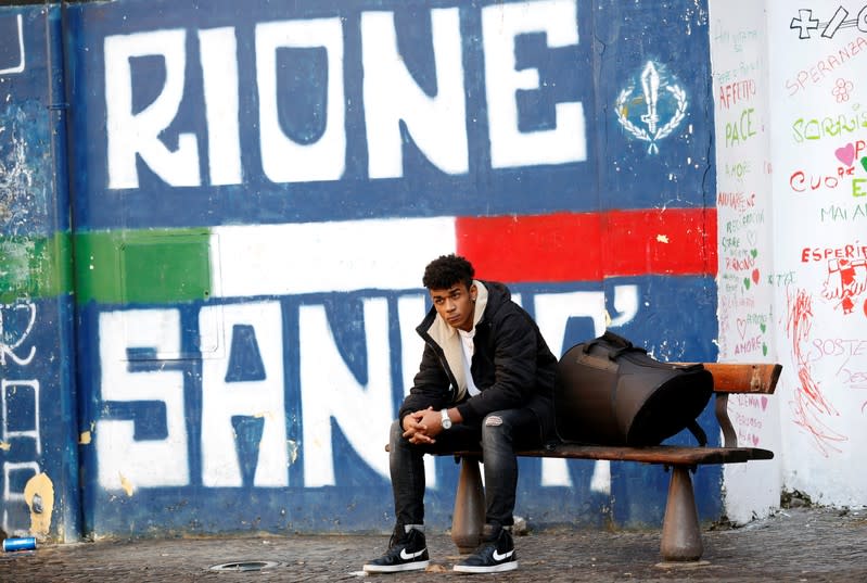 Nico Rodrigues, 21, seats on a bench, with his French horn in a case, outside the Santa Maria della Sanita Basilica in the Rione Sanita neighbourhood in Naples