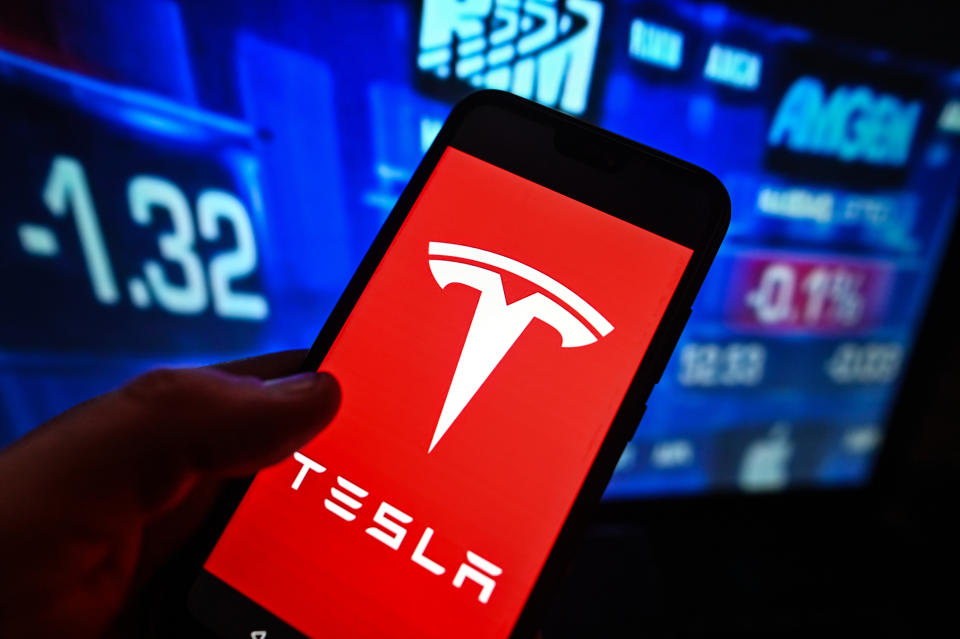 بولندا - 2023/02/02: في هذا الرسم التوضيحي للصورة ، يُعرض شعار Tesla على هاتف ذكي مع وجود النسب المئوية لسوق الأسهم في الخلفية. (توضيح الصورة بقلم عمر ماركيز / SOPA Images / LightRocket عبر Getty Images)