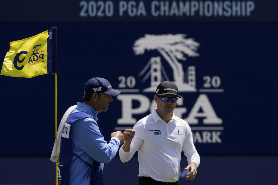 Zach Johnson greets his caddie Brian Smith on the ninth green after their first round of the PGA Championship golf tournament at TPC Harding Park Thursday, Aug. 6, 2020, in San Francisco. (AP Photo/Charlie Riedel)