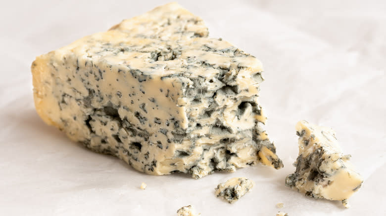 wedge of crumbly blue cheese with a white background