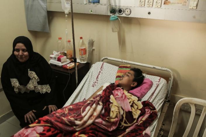 A Palestinian youth wounded at the Israel-Gaza border lies on a bed next to his mother at Shifa Hospital in Gaza City on April 1, 2018 (AFP Photo/MAHMUD HAMS)
