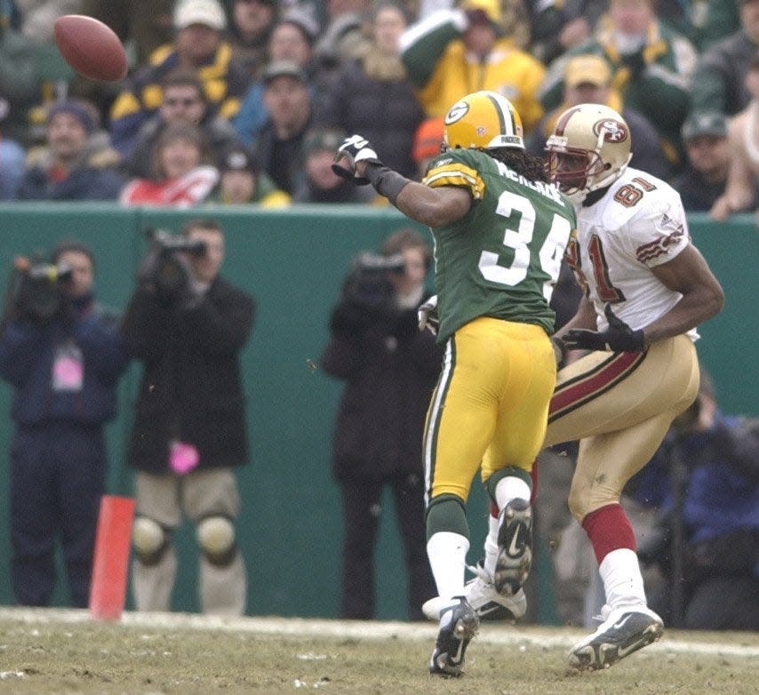 Text: Green Bay Packers Mike McKenzie tips a pass to teammate Tyrone Williams for an interception while covering San Francisco 49ers Terrell Owens during the fourth quarter of their game Sunday, January 13, 2002 at Lambeau Field in Green Bay, Wis.