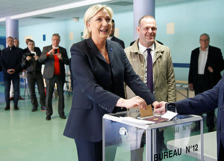 Marine Le Pen (L), French National Front (FN) political party leader and candidate for French 2017 presidential election, casts her ballot in the first round of 2017 French presidential election at a polling station in Henin-Beaumont, northern France, April 23, 2017. At R, Mayor of Henin-Beaumont Steeve Briois. REUTERS/Charles Platiau