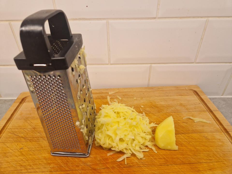 pile of grated potatoes next to a box grater