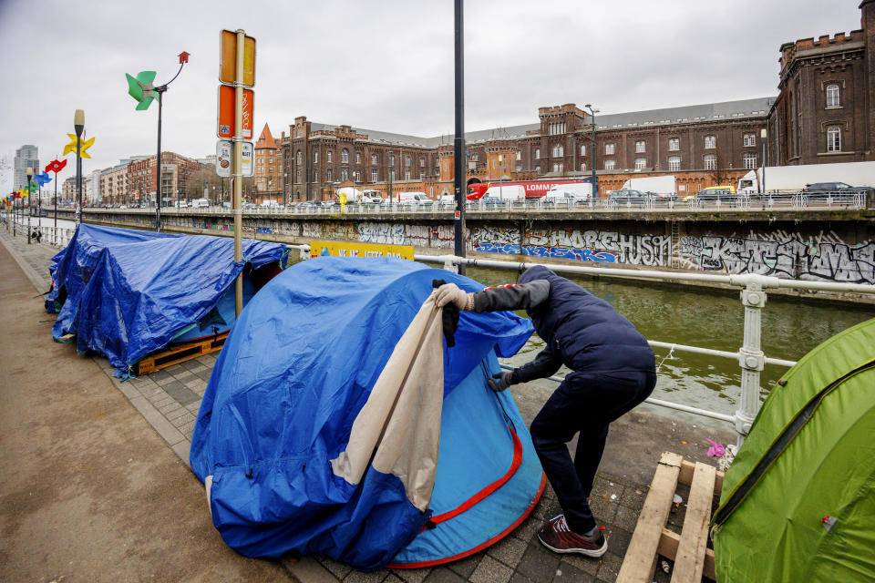 Shinwari, former Afghan army captain and asylum seeker, closes his tent in a makeshift camp outside the Petit Chateau reception center in Brussels, Tuesday, Jan. 31, 2023. Many refugees and asylum-seekers are literally left out in the cold for months as the European Union fails to get its migration system working properly. And most talk is about building fences and repatriation instead of working to improve a warm embrace for people fleeing nations like Afghanistan where the Taliban has taken over. (AP Photo/Olivier Matthys)