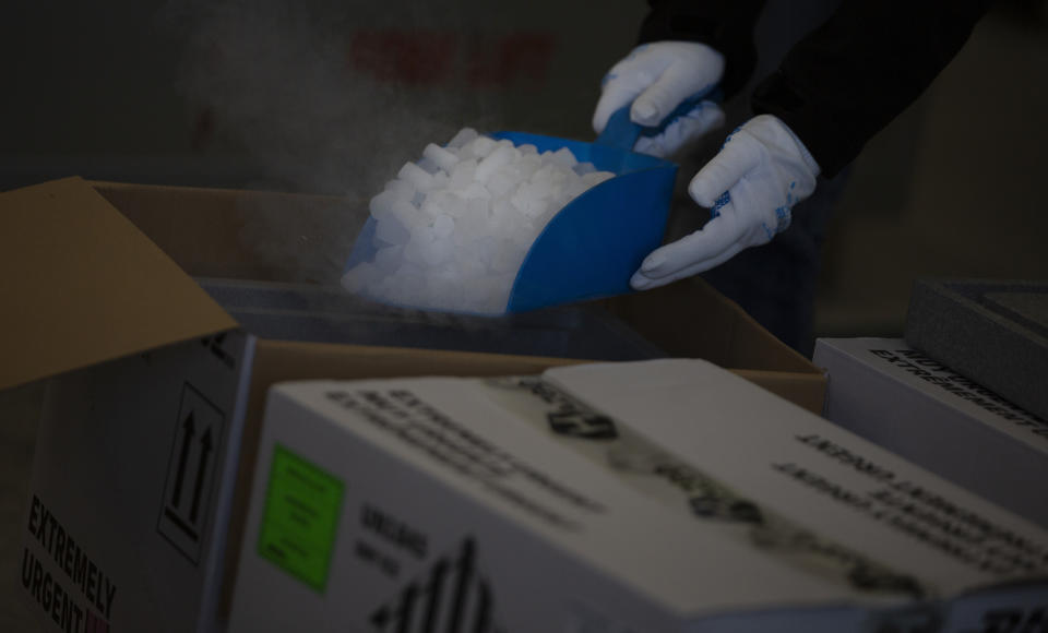 A hazardous goods worker shows how dry ice is used on specific vaccines and medicines to keep them cool during a demonstration of logistics and handling of vaccines and medicines at the DHL cargo warehouse in Steenokkerzeel, Belgium, Tuesday, Dec. 1, 2020. European Commission President Ursula von der Leyen said Tuesday that member states have started working on their vaccination plans and on the logistics for the delivery of tens of millions of doses across the 27-nation bloc. Safely delivering COVID-19 vaccines, once approval has been made, will be the mission of the century for the global air cargo industry. (AP Photo/Virginia Mayo)