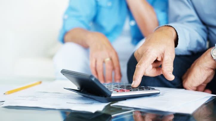 A couple goes over their expenses on a calculator together.