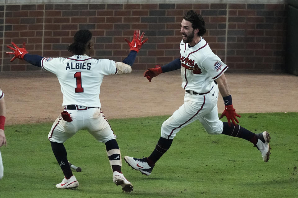 Atlanta Braves' Dansby Swanson, right, celebrates with Atlanta Braves' Ozzie Albies after scoring the winning run on Eddie Rosario's RBI single during the ninth inning against the Los Angeles Dodgers in Game 2 of baseball's National League Championship Series Sunday, Oct. 17, 2021, in Atlanta. The Braves defeated the Dodgers 5-4 to lead the series 2-0 games. (AP Photo/John Bazemore)