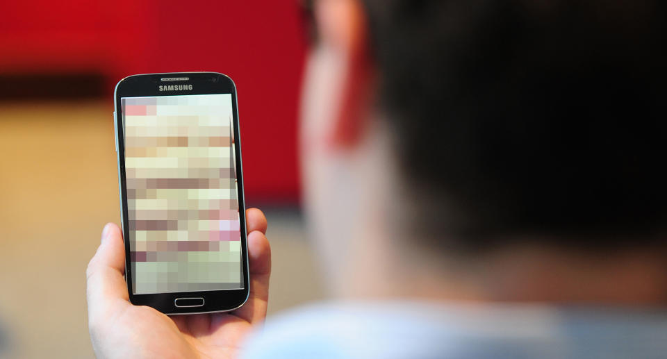 A man holds a mobile with a blurred screen