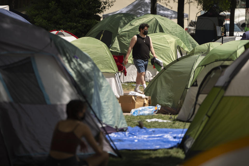 FILE - A person walks through an encampment by students protesting against the Israel-Hamas war at George Washington University on Tuesday, April 30, 2024, in Washington. (AP Photo/Mark Schiefelbein, File)