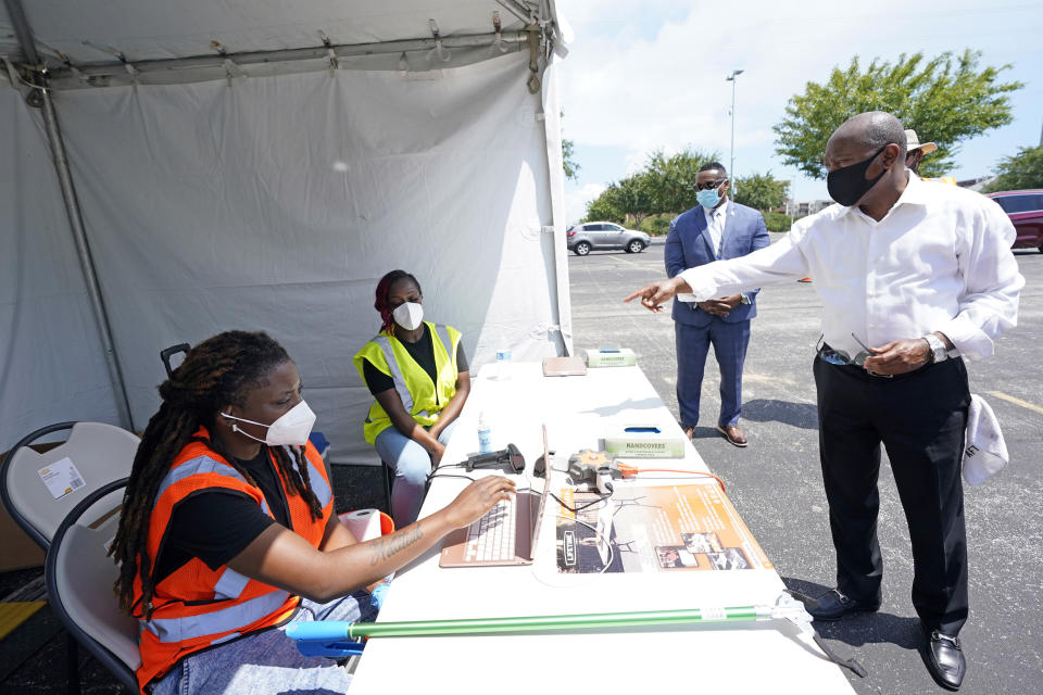 Houston Mayor Sylvester Turner, right, talks with healthcare workers at a Texas Division of Emergency Management free COVID-19 testing site at Minute Maid Park Saturday, Aug. 8, 2020, in Houston. UNICEF-USA is teaming up with Turner for the organization's first-ever initiative to support kids in the U.S. (AP Photo/David J. Phillip)